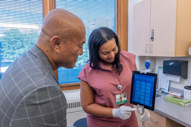 Clinician with a patient in an exam room using an translation service on an electronic tablet 